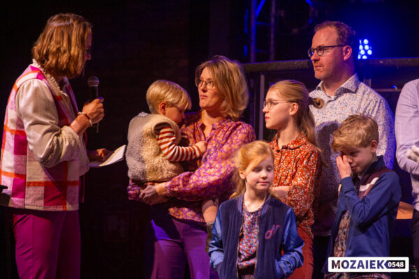 Gezinnen met hun kinderen staan op het podium tijdens een opdraagdienst van Mozaiek0548