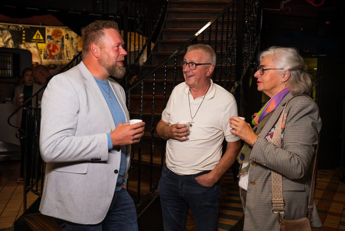 Drie mensen in gesprek met een kop koffie in de hal van Mozaiek0548