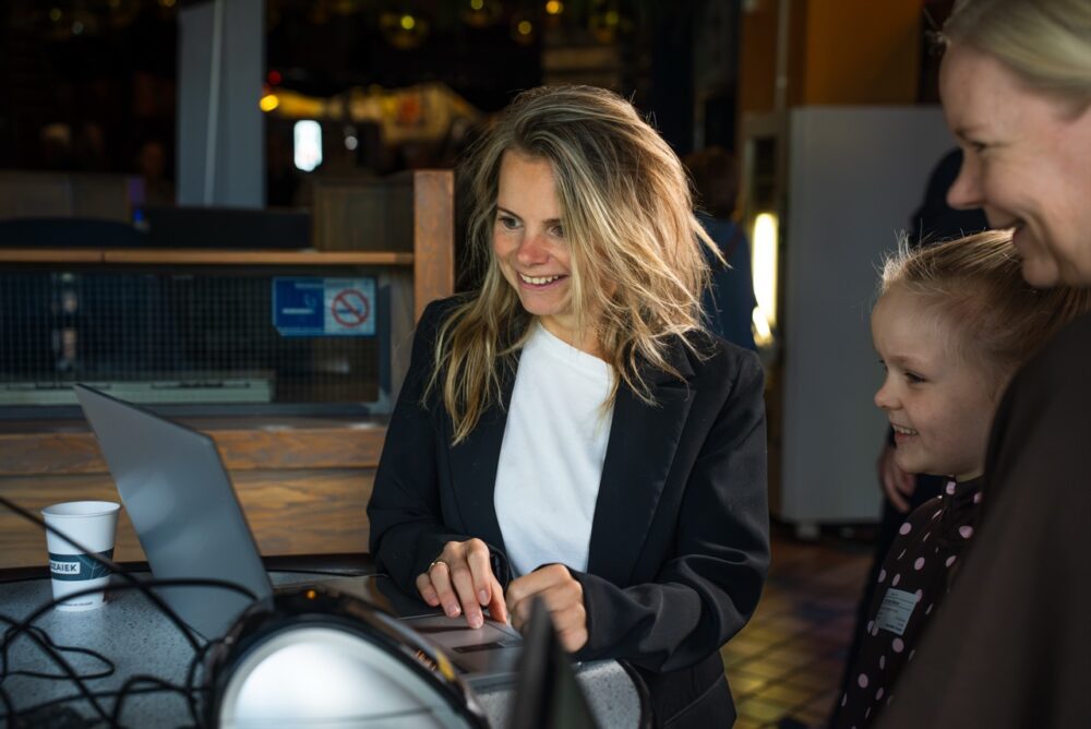 Vrouw achter de koffiebar lacht naar een kind bij Mozaiek0548